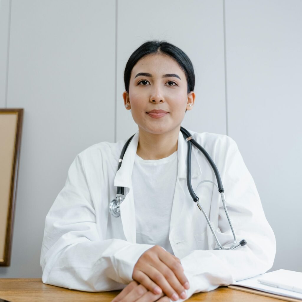 A female doctor confidently sits at her desk, ready for consultation in a medical office.
