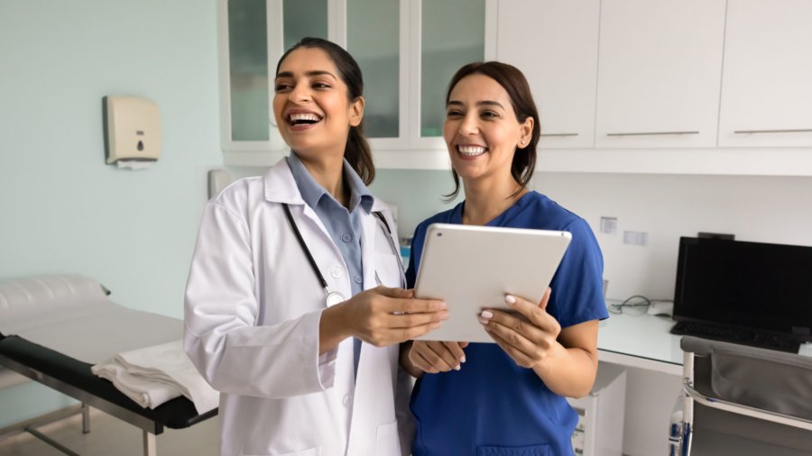 two happy diverse female doctor colleagues using digital tablet