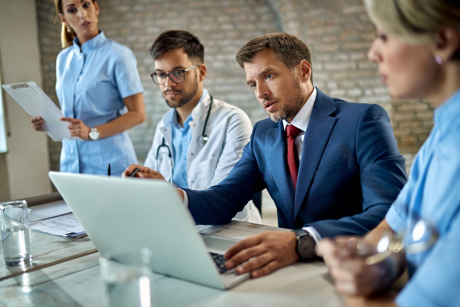 Mid adult businessman and healthcare workers cooperating while working on a computer during a meeting in the office.