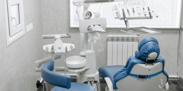 A clean and modern dental office featuring a dental chair, equipment, and bright lighting.